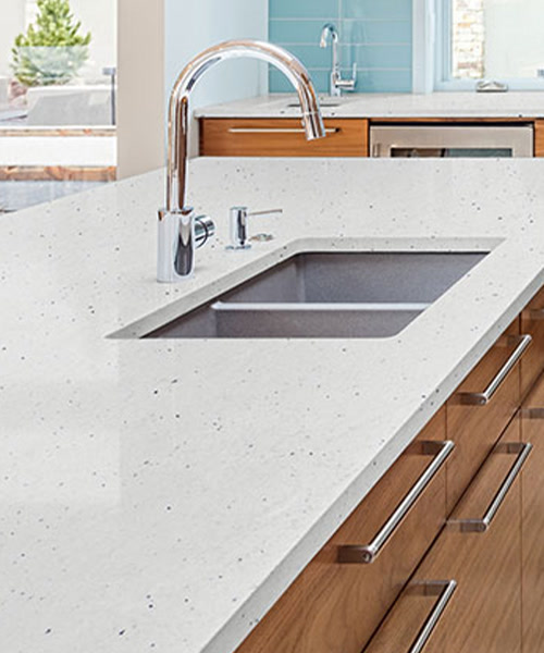 Speckled white granite countertop with an undermount sink over walnut drawers